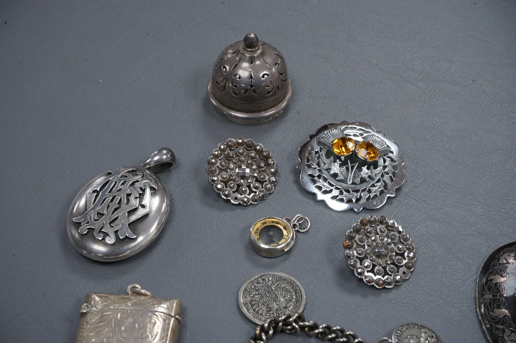 A mixed group of assorted collectables including a silver vesta case, two Victorian white metal lockets, two cut steel buttons, a coin bracelet and three other items.
